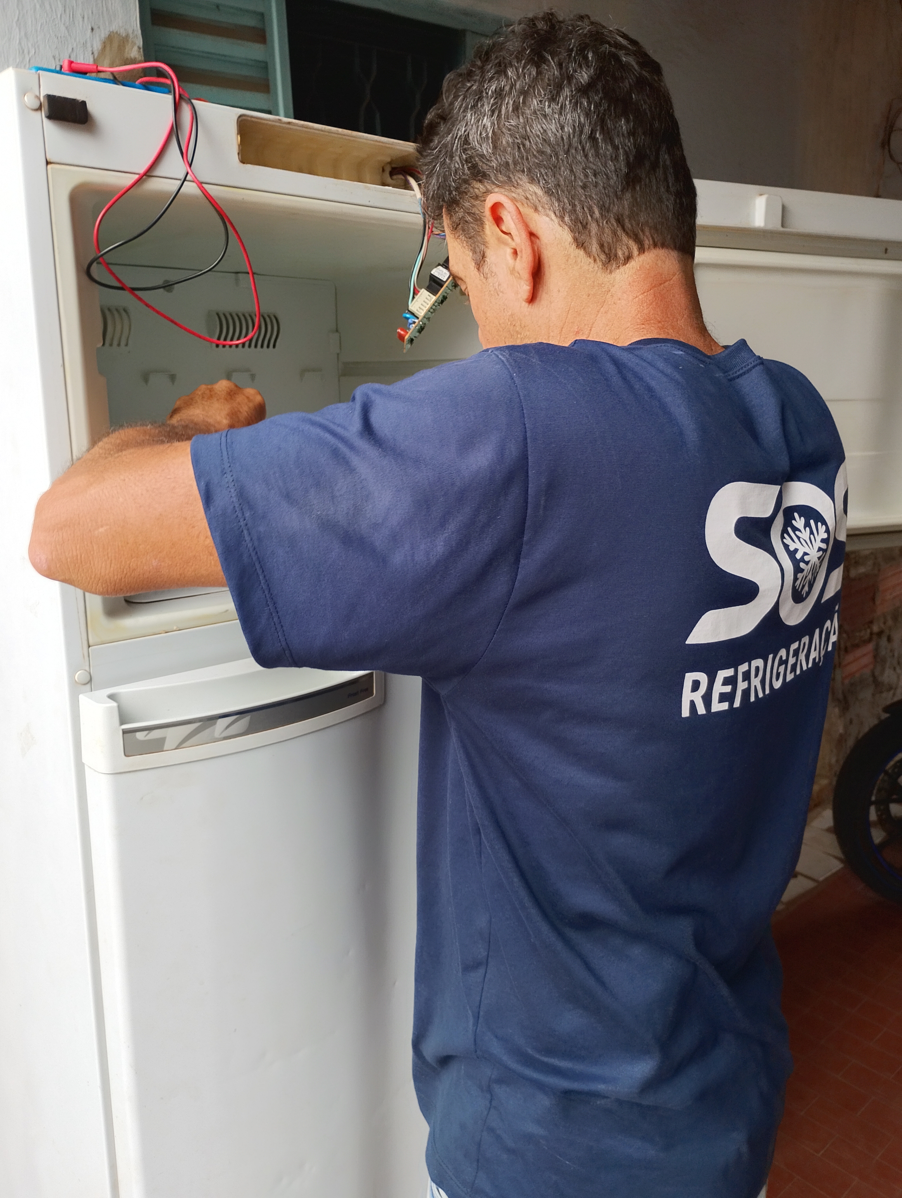 Técnico SOS Refrigeração consertando geladeira em Ituiutaba